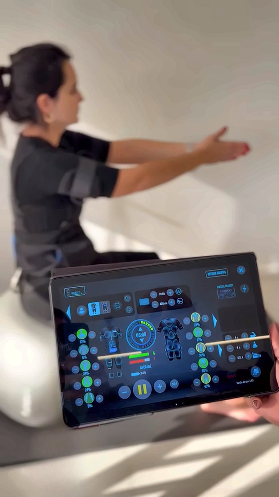Fisioterapeuta ajustando a intensidade do Eletropilates pelo tablet